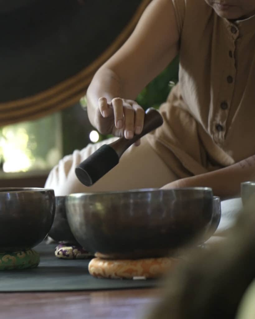Therapist playing Tibetan singing bowls during a sound healing session