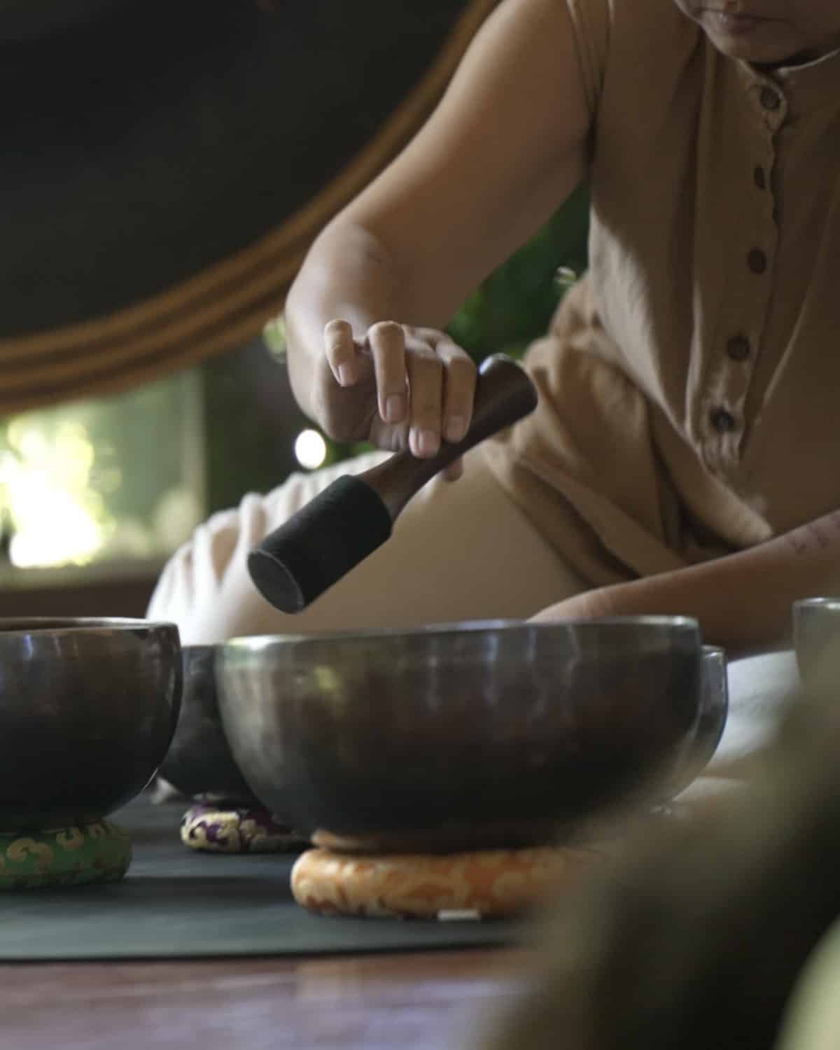 Therapist playing Tibetan singing bowls during a sound healing session